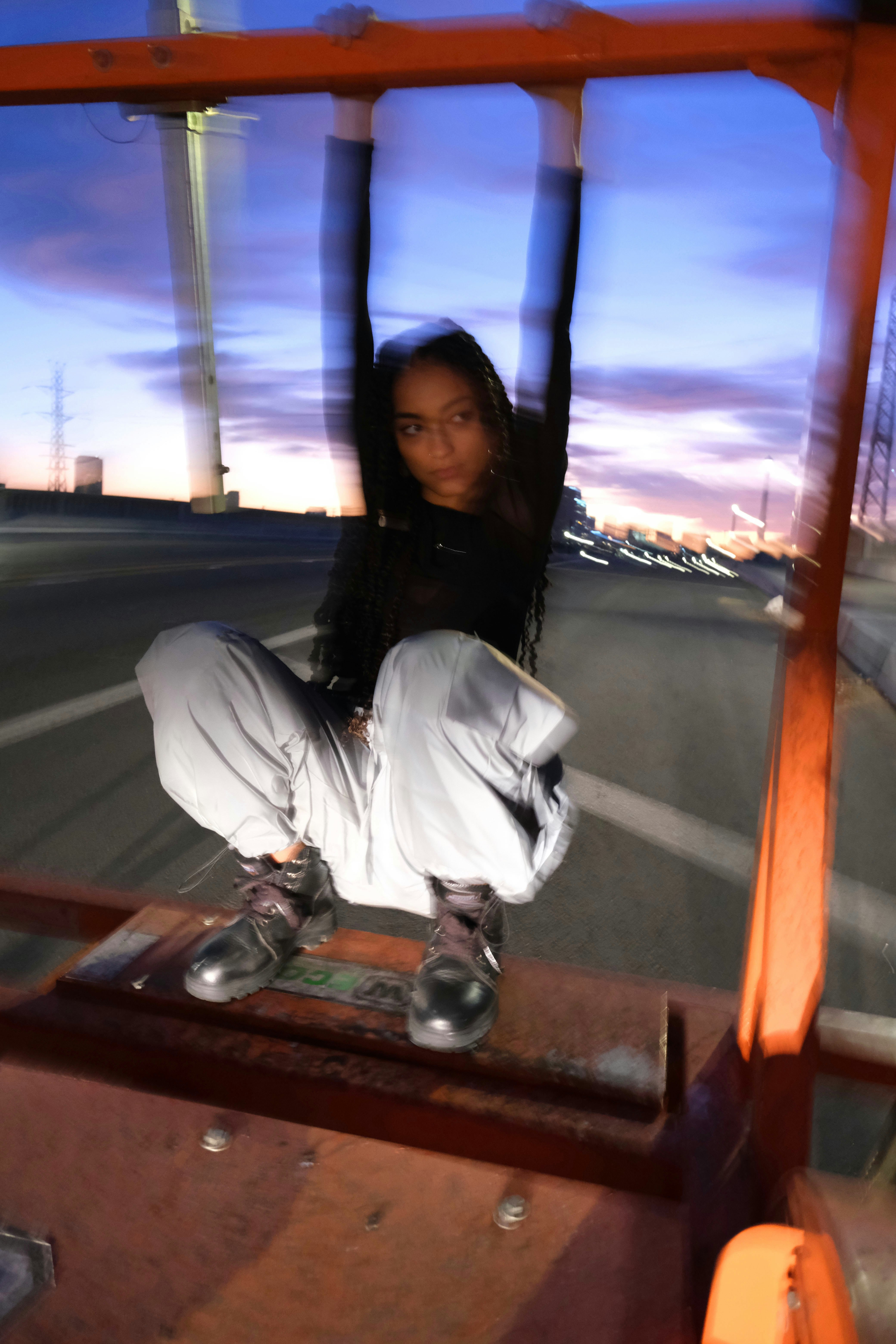 woman in black jacket and white pants sitting on brown wooden bench